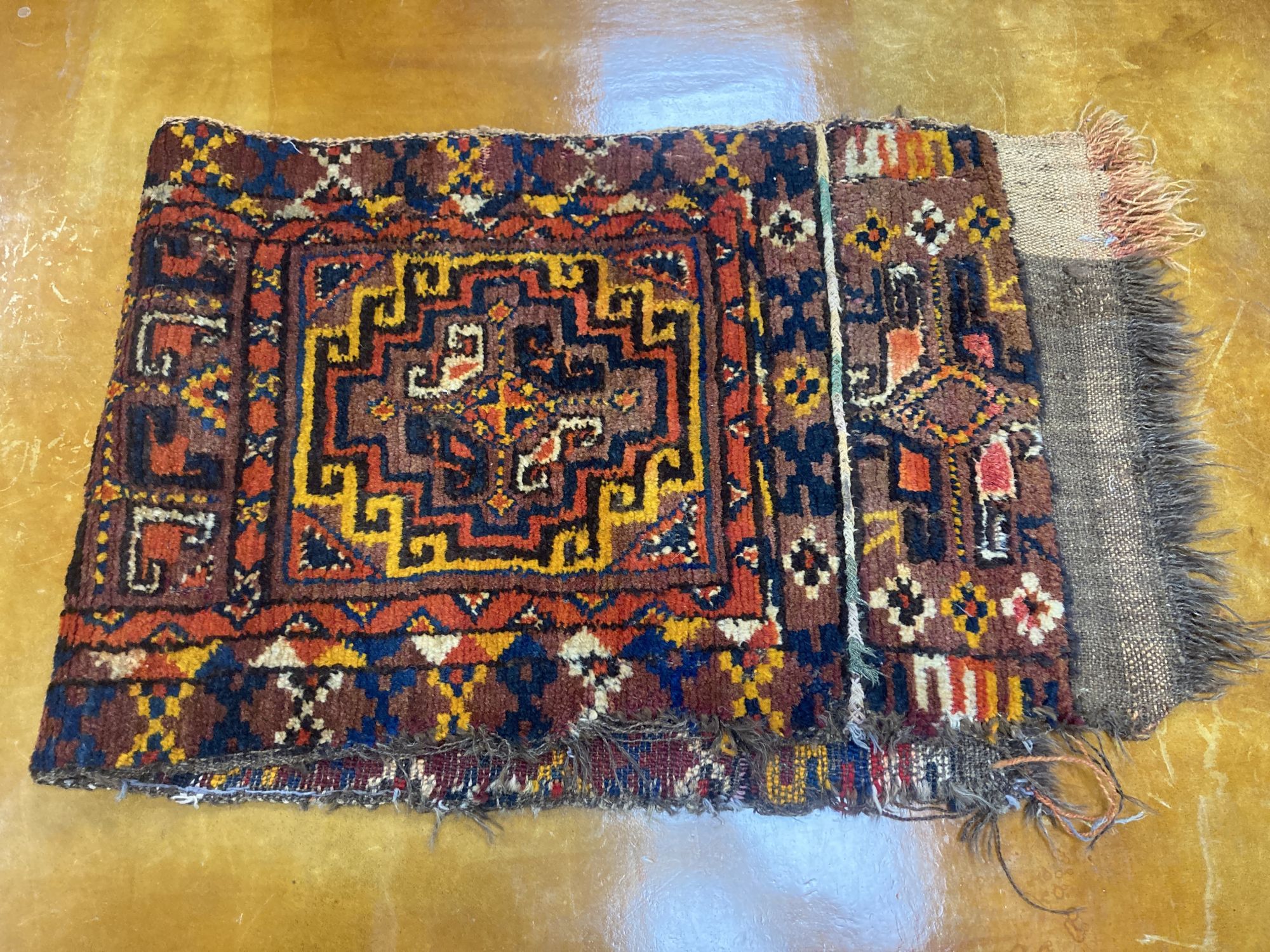 Six Caucasian design mats and a saddlebag, largest 140 x 60cm